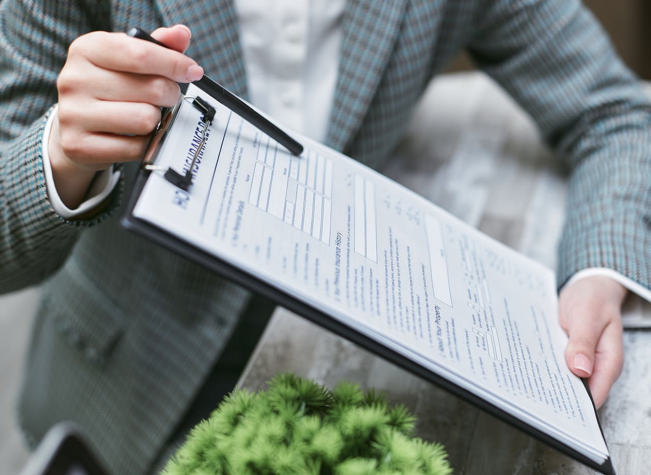 Services-02 Close-up of a businessperson holding a clipboard with an insurance document, emphasizing details.